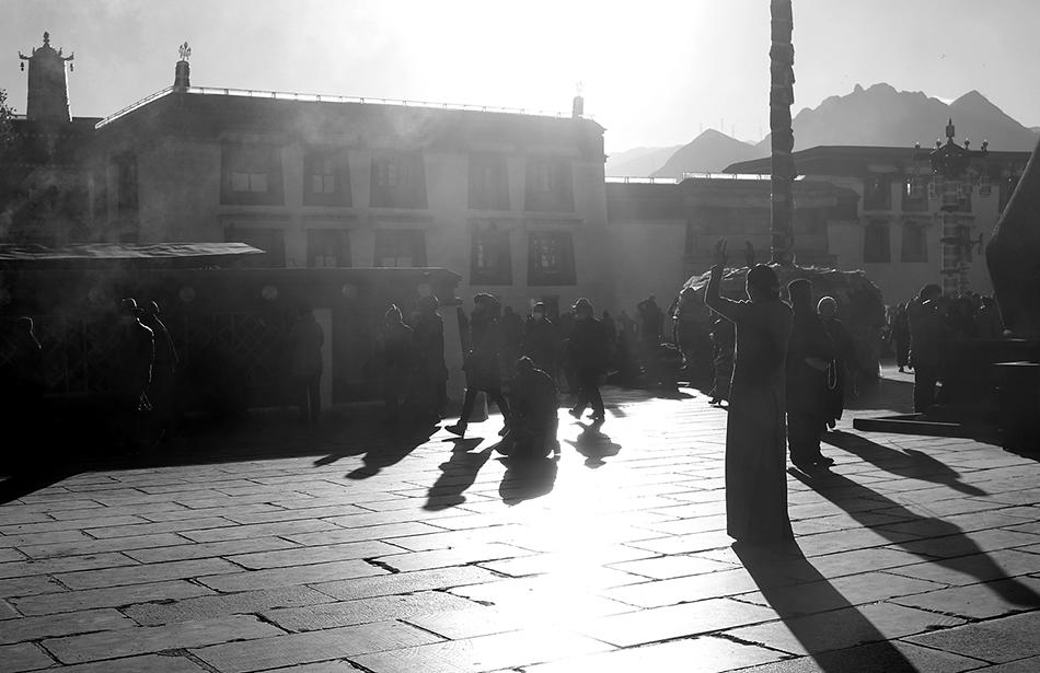 Worshippers outside Jokhang Monastery. The late afternoon sunlight cast a beautiful silhouette and shadows of worshippers on the square outside the monastery. Taken with Fujifilm X100T.