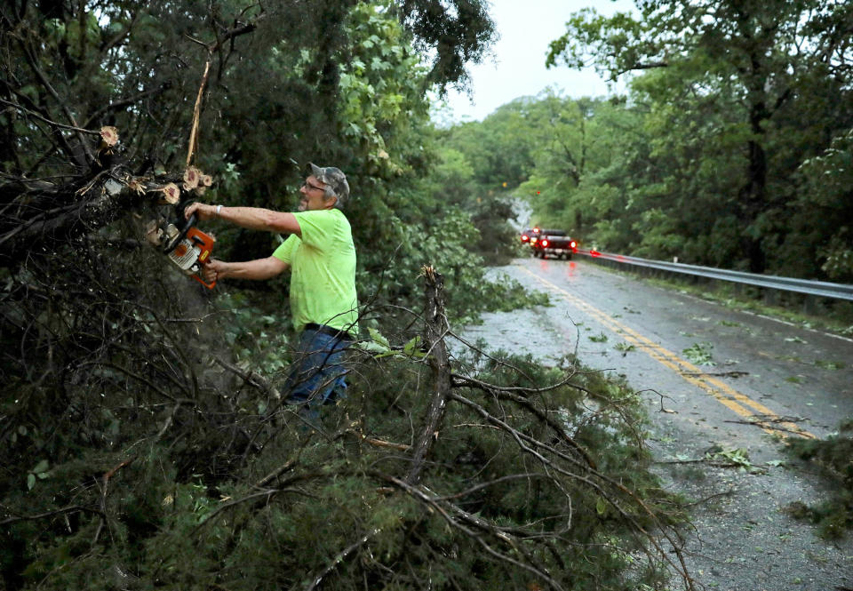 Tony Brinker, a volunteer with the Augusta Fire Protection District, cuts trees that were blocking Highway 94, Tuesday, May 21, 2019, near Augusta, Mo. A long north-south line of storms hit the St. Louis area Tuesday evening. The storms are part of a weather system moving across the Midwest that began last weekend and will continue through the week, according to the National Weather Service. (David Carson/St. Louis Post-Dispatch via AP)