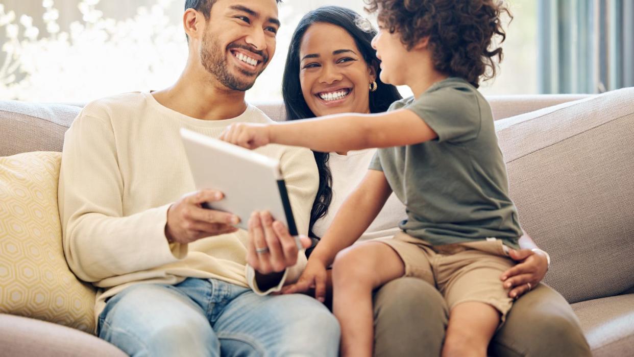 shot of a little boy using a digital tablet while sitting at home with his parents