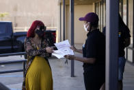 Tonya Freeman Brown, right, of the national nonprofit Resilience Force, hands a flyer to Darlene Poole, who helps run a family-owned nonprofit business engaging youth, in New Orleans, Monday, Oct. 5, 2020. Resilience Force trains and puts to work people in the areas of disaster recovery and rebuilding with focus on Black and minority communities. (AP Photo/Gerald Herbert)