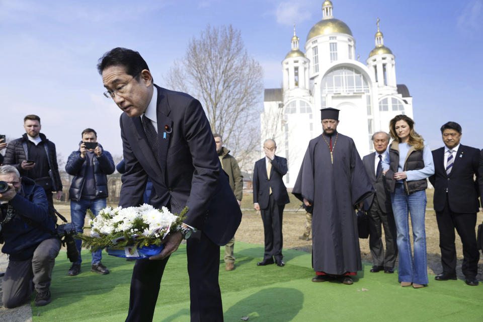 Japanese Prime Minister Fumio Kishida, front, lays the flowers at a church in Bucha, a town outside Kyiv that became a symbol of Russian atrocities against civilians, in Ukraine, Tuesday, March 21, 2023.(Iori Sagisawa/Kyodo News via AP)