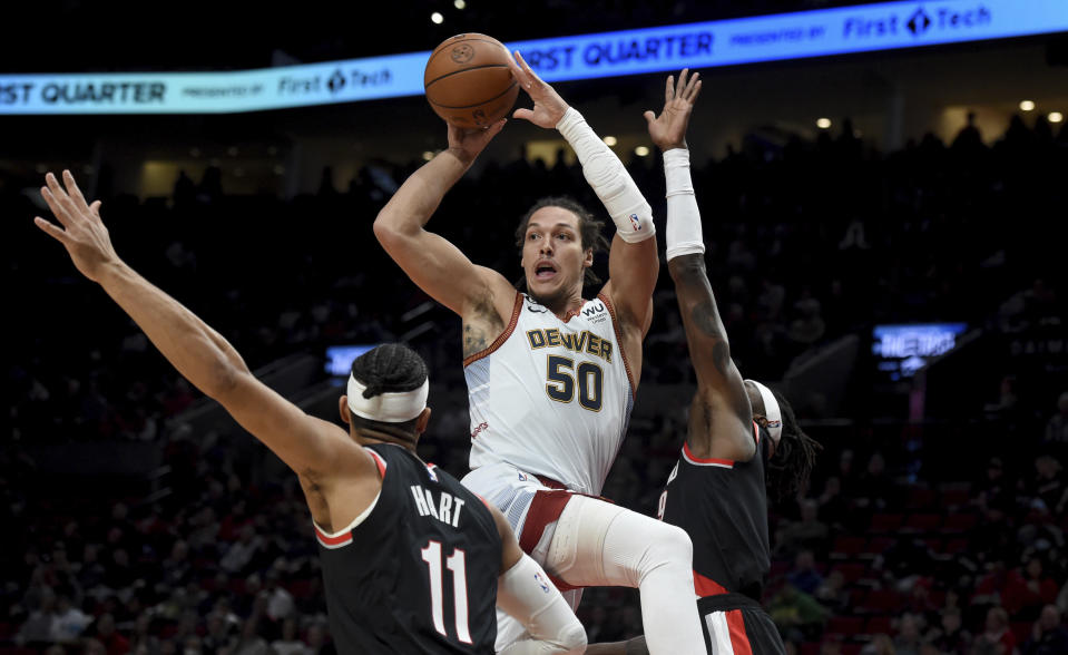 Denver Nuggets forward Aaron Gordon, center, drives to the basket as Portland Trail Blazers guard Josh Hart, left, and forward Jerami Grant defend during the first half of an NBA basketball game in Portland, Ore., Thursday, Dec. 8, 2022. (AP Photo/Steve Dykes)