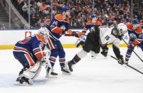 Arizona Coyotes' Alexander Kerfoot (15) is checked by Edmonton Oilers' Mattias Ekholm (14) as goalie Calvin Pickard (30) looks for the shot during the third period of an NHL hockey game Friday, April 12, 2024, in Edmonton, Alberta. (Jason Franson/The Canadian Press via AP)