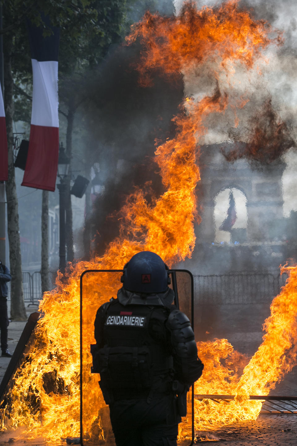 A riot police officer takes position on the Champs-Elysees avenue during scuffles with demonstrators after Bastille Day parade Sunday, July 14, 2019 in Paris. (AP Photo/Rafael Yaghobzadeh)