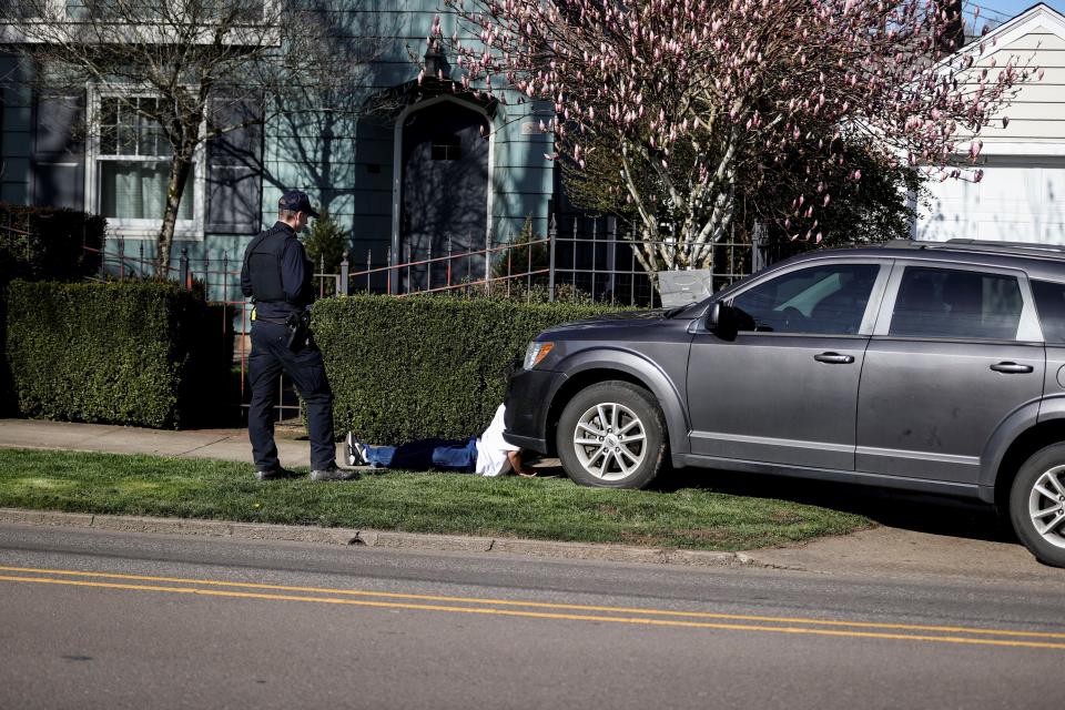 A teenager is seen in handcuffs along Mission Street SE on Thursday afternoon as police shooting that left one dead and two wounded at the south end of Bush's Pasture Park.