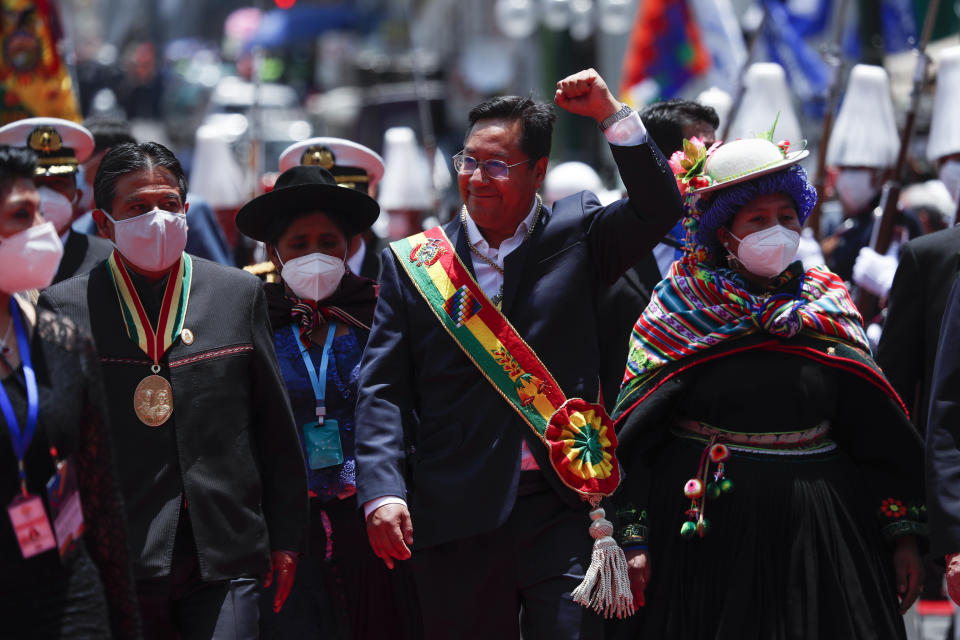 Bolivia's new President Luis Arce, center, raises his fist as he walks with Vice President David Choquehuanca, left, on their inauguration day in La Paz, Bolivia, Sunday, Nov. 8, 2020. (AP Photo/Juan Karita)