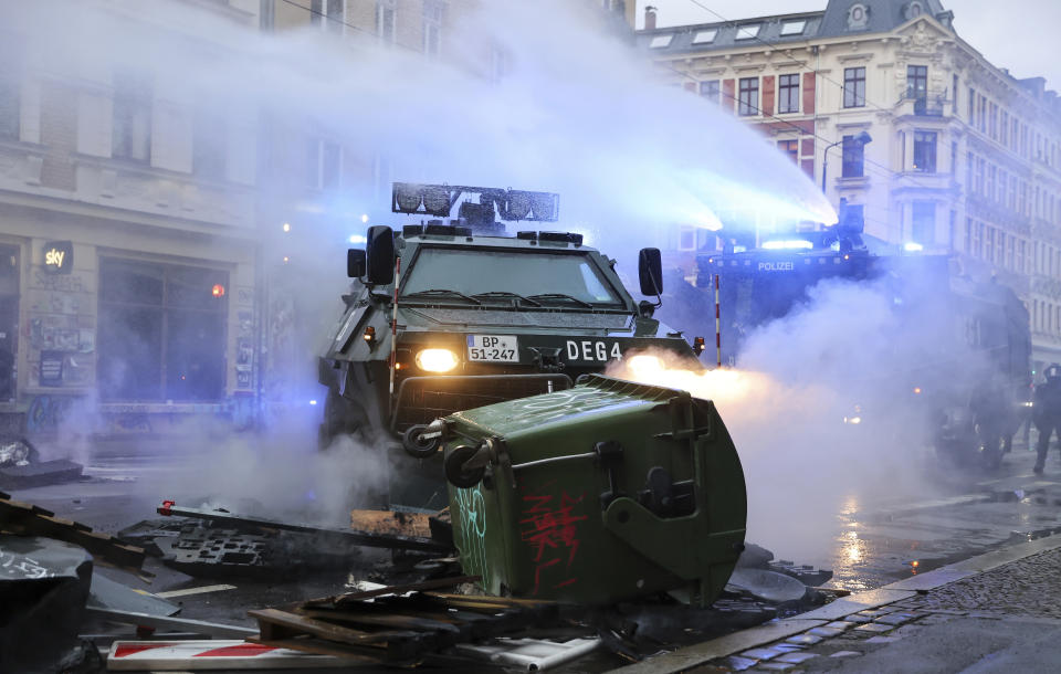 A water cannon and an evacuation tank clear a barricade on Wolfgang-Heinze-Strasse after riots broke out at the end of a left-wing demonstration, in Leipzig, Germany, Saturday, Sept. 18, 2021. The campaign alliance "We are all Linx" had mobilized nationwide for the demonstration. (Jan Woitas/dpa via AP)