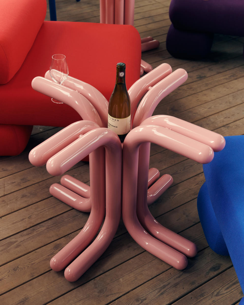 A pink abstract wine table holding a bottle of wine and glasses