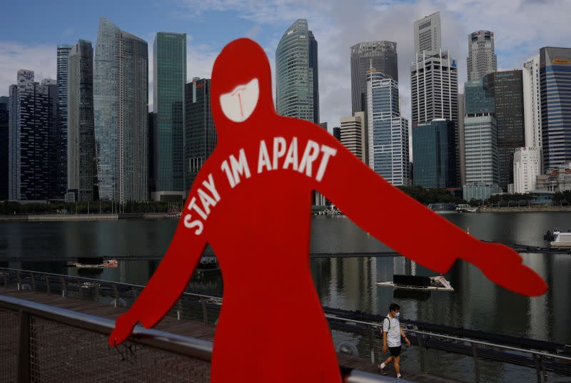 A man wearing a face mask passes a sign put up to encourage social distancing during the coronavirus disease (COVID-19) outbreak, at Marina Bay in Singapore