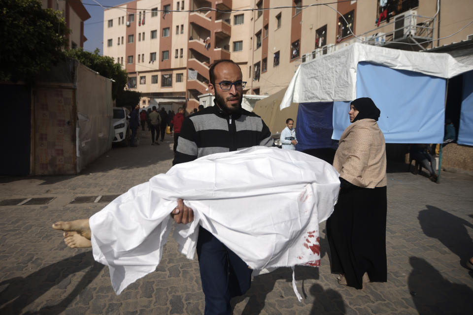 A Palestinian man carries the body of a child killed in the Israeli bombardment of the Gaza Strip, at Nasser hospital in Khan Younis, Monday, Jan. 22, 2024. (AP Photo/Mohammed Dahman)