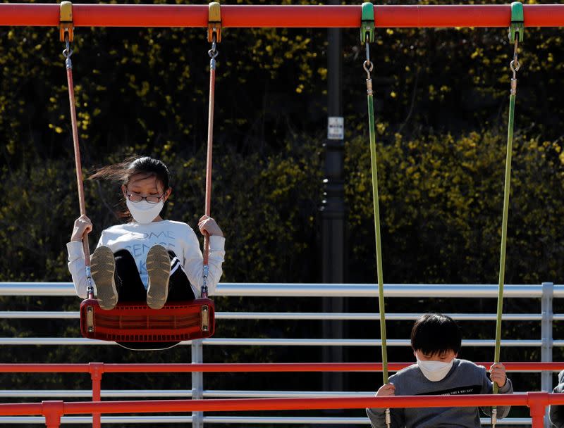 Children wearing masks following the rise in confirmed cases of coronavirus disease (COVID-19), play on the swings at a park in Daegu