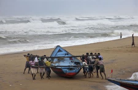 Fishermen move a fishing boat to a safer place along the shore ahead of cyclone Hudhud at Ganjam district in Odisha October 11, 2014. REUTERS/Stringer