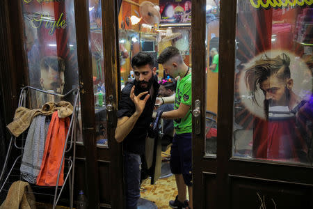 A man talks to a costumer as he stands inside his barber shop in the Old City of Damascus, Syria, September 13, 2018. REUTERS/Marko Djurica