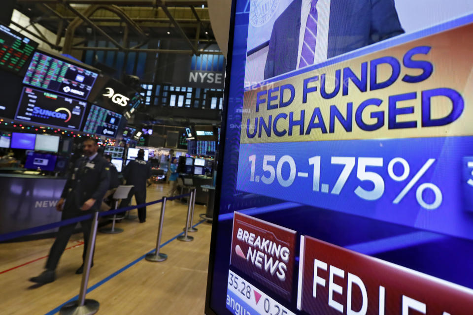 A television screen on the floor of the New York Stock Exchange shows the rate decision of the Federal Reserve, Wednesday, Dec. 11, 2019. The Federal Reserve is leaving its benchmark interest rate alone and signaling that it expects to keep low rates unchanged through next year. (AP Photo/Richard Drew)