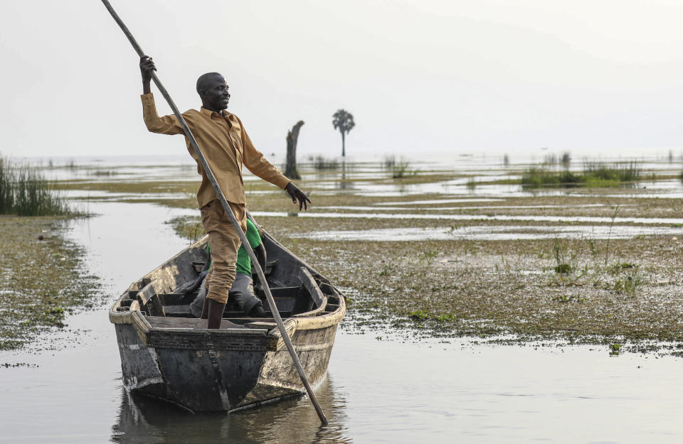 John Gafabusa, custodian of the Mutyona natural sacred site near Buliisa, Uganda, points at a water covered sacred site on Lake Albert at the Karakaba landing site, Aug. 3, 2023. As TotalEnergies invests billions into oilfield development and acquires more and more land, Bagungu people who practice traditional beliefs worry the spiritual power of at least 32 sacred natural sites in Buliisa keeps deteriorating. (AP Photo/Hajarah Nalwadda)