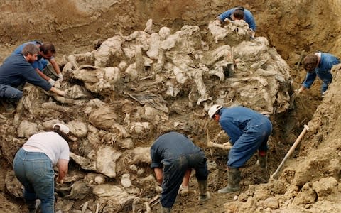 International War Crimes Tribunal investigators clearing away soil and debris from dozens of Srebrenica victims buried in a mass grave near the village of Pilica - Credit: Staton Winter / AP