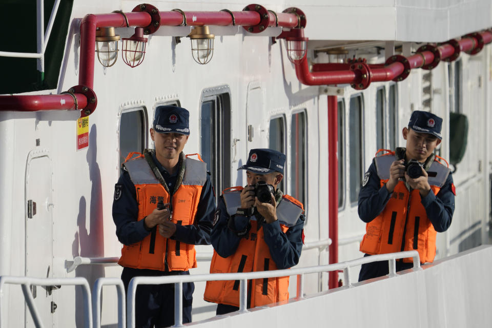 Chinese coast guard crew members take pictures as they block the path of Philippine coast guard BRP Sindangan while it tried to enter the Second Thomas Shoal, locally known as Ayungin Shoal, in the disputed South China Sea Tuesday, March 5, 2024. Chinese and Philippine coast guard vessels collided in the disputed South China Sea and multiple Filipino crew members were injured in high-seas confrontations Tuesday as Southeast Asian leaders gathered for a summit that was expected to touch on Beijing's aggression at sea. (AP Photo/Aaron Favila)