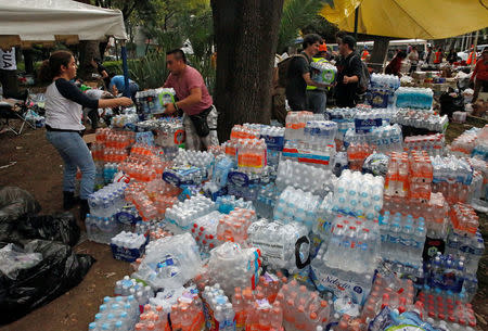 Unas personas distribuyendo botellas de agua y otros elementos de ayuda en una calle ubicada junto a un edificio derruido tras un sismo en Ciudad de México, sep 20, 2017. REUTERS/Henry Romero