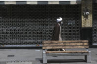 A cleric walks past a closed shop of Tehran's Grand Bazaar, Iran, Saturday, April 10, 2021. Iran on Saturday imposed partial lockdown on businesses in major shopping centers as well as intercity travels through personal cars in major cities including capital Tehran as it struggles with the worst outbreak of the coronavirus in the Mideast region. (AP Photo/Vahid Salemi)