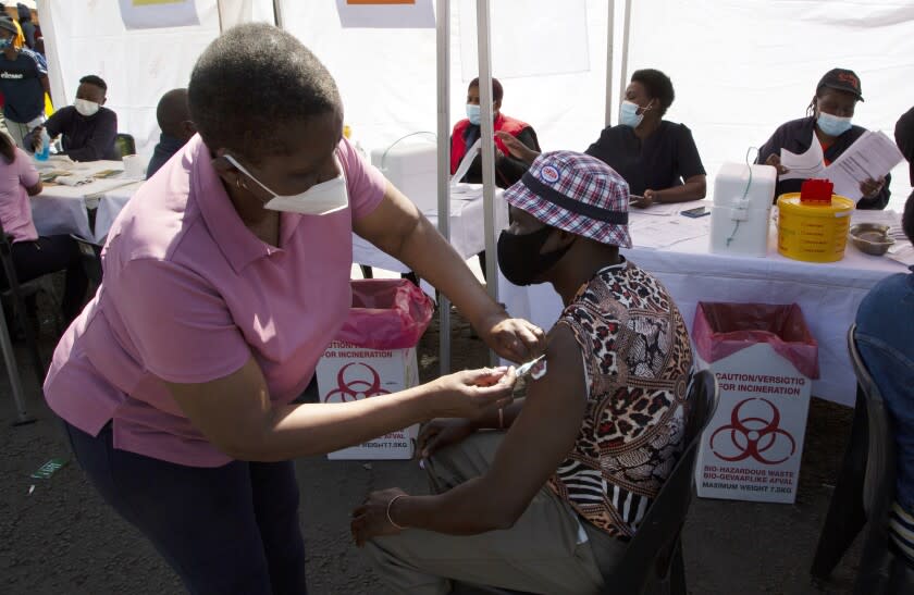 A patient receives a Johnson & Johnson vaccine at a pop-up vaccination centre, at the Bare taxi rank in Soweto, South Africa, Friday, Aug. 20, 2021. Faced with slowing numbers of people getting COVID-19 jabs, South Africa has opened eligibility to all adults to step up the volume of inoculations as it battles a surge in the disease driven by the delta variant. (AP Photo/Denis Farrell)