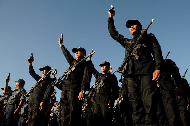 Philippine police hold up their firearms during a ceremony in Manila, on December 29, 2012. Short people hoping to join the long arm of the law in the Philippines will be left disappointed after President Benigno Aquino vetoed a bill removing height requirements for the police