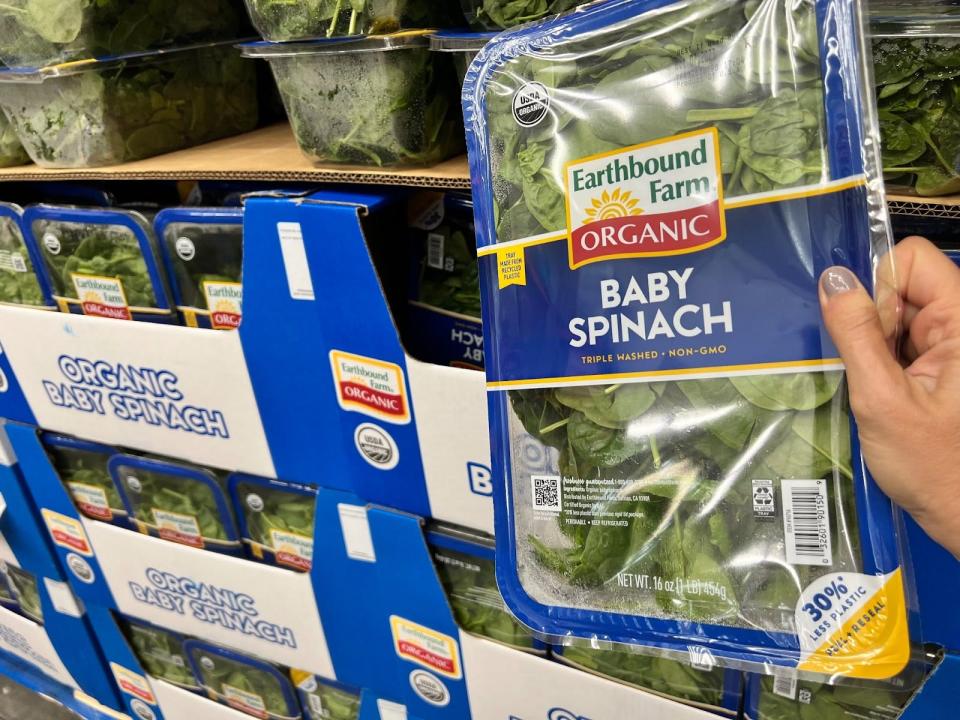 hand holding up a box of baby spinach in costco