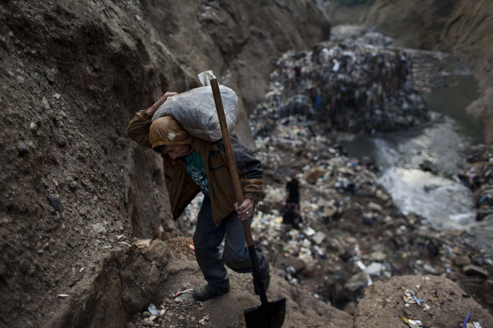 <p>In this photo taken on Wednesday Oct. 5, 2011, a man who gave only his first name, Wilmer, carries a sack of metal he collected after working the entire day at the bottom of one of the biggest trash dumps in the city, known as “the Mine,” in Guatemala City. (Photo: Rodrigo Abd/AP) </p>