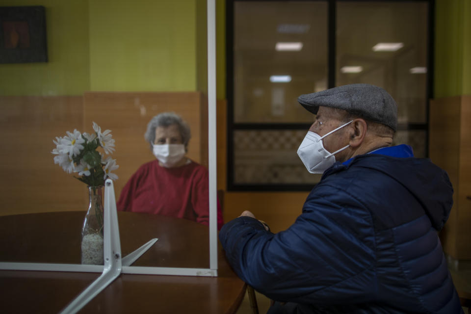 Residents meet with their families through a glass to protect themselves against COVID-19 at DomusVi nursing home in Leganes, Spain, Wednesday, March 10, 2021. Spain is preparing to tighten some pandemic restrictions on movement during the approaching Easter holiday, which is a traditional period for family visits. (AP Photo/Manu Fernandez)