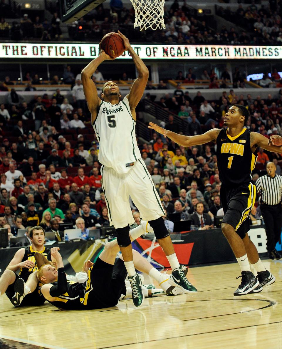 A rough-and-tumble 2013 Big Ten Tournament matchup between Michigan State and Iowa is depicted in this photo, as the Spartans' Adreian Payne (5) shoots against Iowa during a 59-56 win. Zach McCabe and Mike Gesell are on the ground; Melsahn Basabe is trailing.