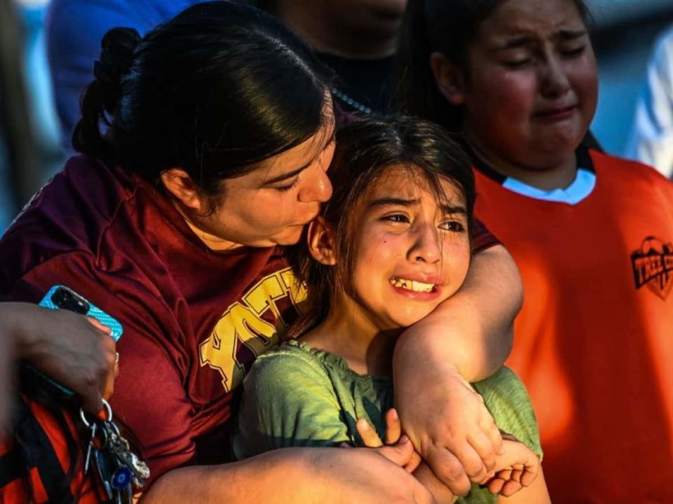 Gabriella Uriegas, a soccer teammate of Tess Mata, who died in the shooting at Robb Elementary School, cries while holding her mother, Geneva Uriegas, as they visit a makeshift memorial outside the Uvalde County Courthouse in Texas. Parents say children who witnessed the shooting or have friends or relatives who died are struggling to process the tragedy. (Chandan Khanna/AFP/Getty Images - image credit)