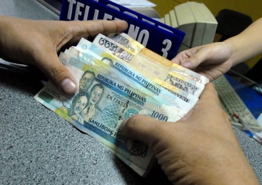 FILE PHOTO: A customer holds Philippine peso notes during a bank transaction in Manila. (Photo: Getty Images)
