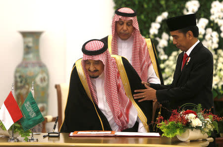 Indonesian President Joko Widodo assists Saudi Arabia's King Salman as he takes his seat at the Presidential Palace in Bogor, West Java, Indonesia March 1, 2017. REUTERS/Adi Weda