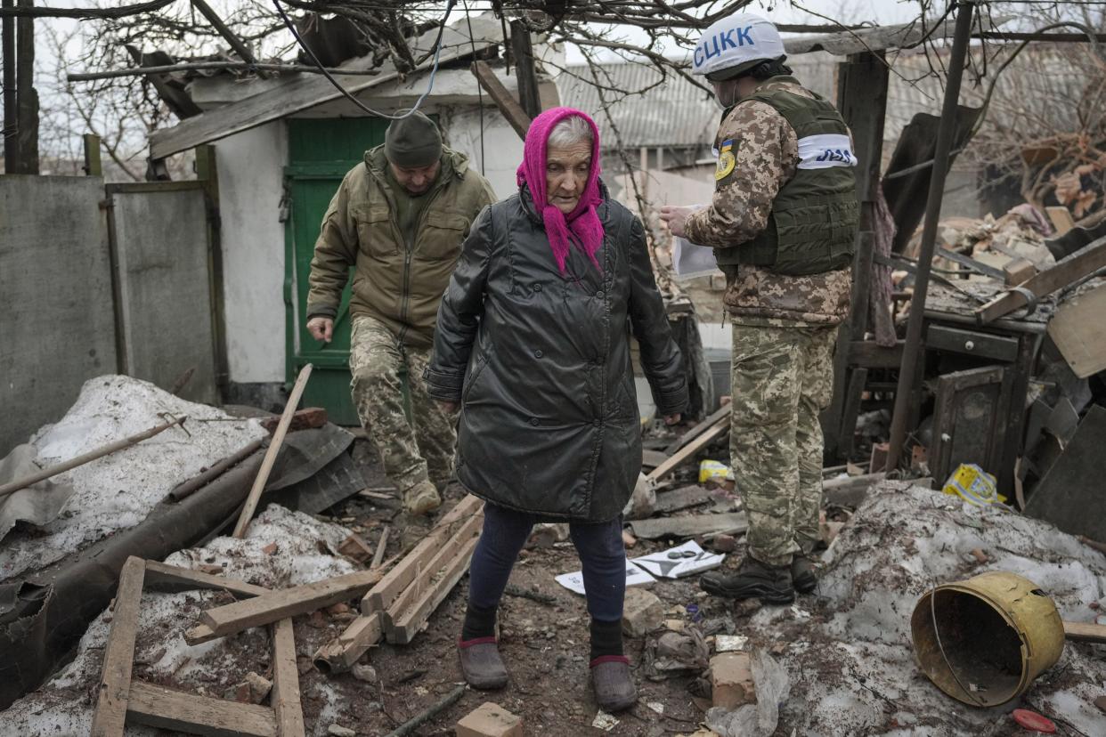 Valentyna Melnychenko walks with members of the Joint Centre for Control and Coordination on ceasefire of the demarcation line, or JCCC, who survey damage to her home from an artillery shell that landed in Vrubivka, one of the at least eight that hit the village today, according to local officials, in the Luhansk region, eastern Ukraine, Thursday, Feb. 17, 2022. U.S. President Joe Biden warned that Russia could still invade Ukraine within days and Russia expelled the No. 2 diplomat at the U.S. Embassy in Moscow, as tensions flared anew in the worst East-West standoff in decades.