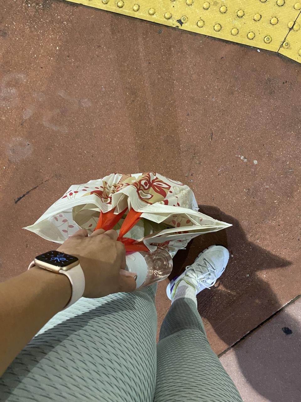 the author holding plastic shopping bags and a water bottle