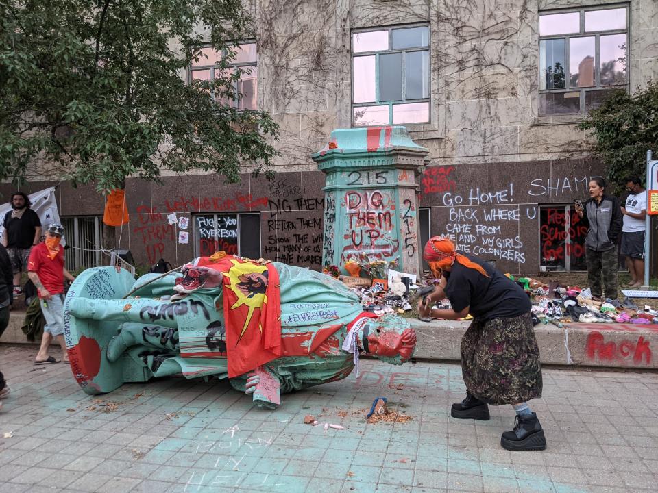 <p>A woman hammers the toppled statue of Egerton Ryerson, one of the architects of indigenous boarding school system, in Toronto on June 6, 2021. (Photo by OLIVIER MONNIER/AFP via Getty Images)</p> 