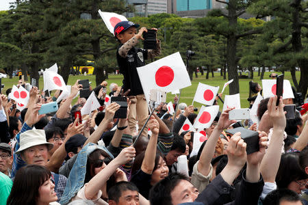 People wave flags and take pictures as the motorcade transporting Japan's Emperor Naruhito leaves the Imperial Palace in Tokyo, Japan May 1, 2019. REUTERS/Kim Kyung-Hoon