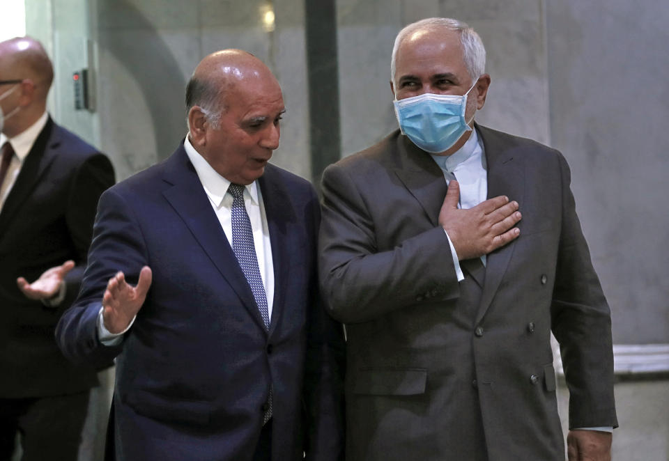 Iranian Foreign Minister, Mohammad Javad Zarif, right, wears a mask to help prevent the spread of the coronavirus walks with his Iraqi counterpart, Fouad Hussein during his visit to Baghdad, Iraq, Sunday, July 19, 2020. (AP Photo/Hadi Mizban)