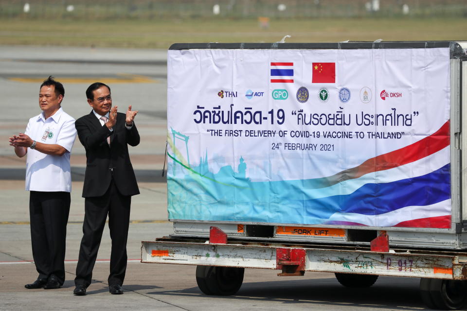 Thailand's Prime Minister Prayuth Chan-ocha and Public Health Minister Anutin Charnvirakul applaud next to a container as they attend the arrival of a plane with a shipment of 200,000 doses of the Sinovac coronavirus disease (COVID-19) vaccine from China at Bangkok's Suvarnabhumi International Airport, Thailand, February 24, 2021. REUTERS/Athit Perawongmetha     TPX IMAGES OF THE DAY