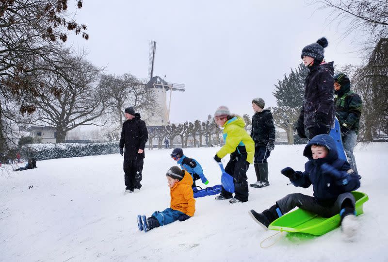 FILE PHOTO: Children sled near a windmill as it snows in Nijmegen