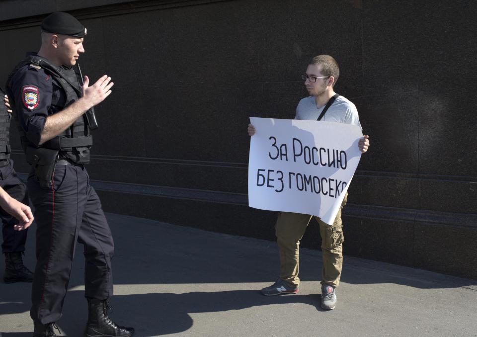 A police officer speaks with a demonstrator near the State Duma, Russia's lower parliament chamber, in Moscow Tuesday, June 11, 2013. A controversial bill banning "homosexual propaganda" is expected to be approved by Russia's lower house of parliament for the second and third of three hearings on Tuesday. Poster reads: "For Russia without homosexuals." (AP Photo/Alexander Zemlianichenko)