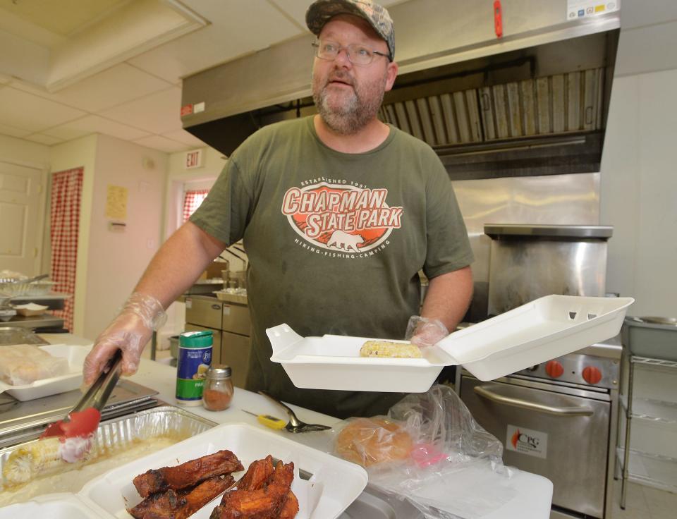 Skinny Nate's BBQ owner Nate Mitchell, 41, prepares an order of baby-back ribs and street sweet corn during a soft opening of the new restaurant in Albion.