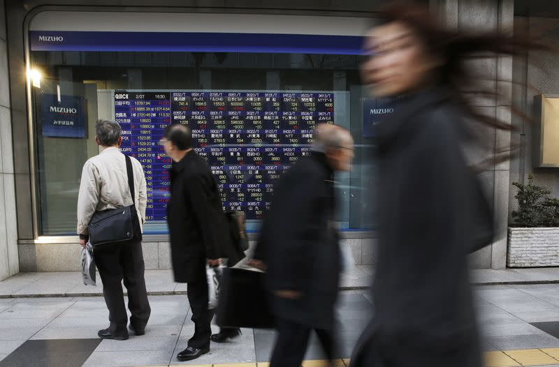A man (L) looks at a stock quotation board as passers-by walk past, outside a brokerage in Tokyo February 27, 2015. REUTERS/Toru Hanai