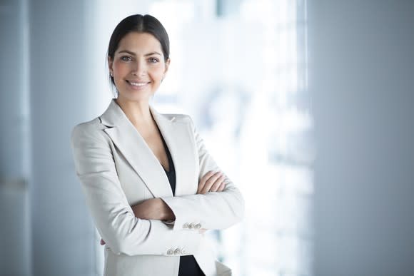 woman in white business suit smiling with arms crossed.