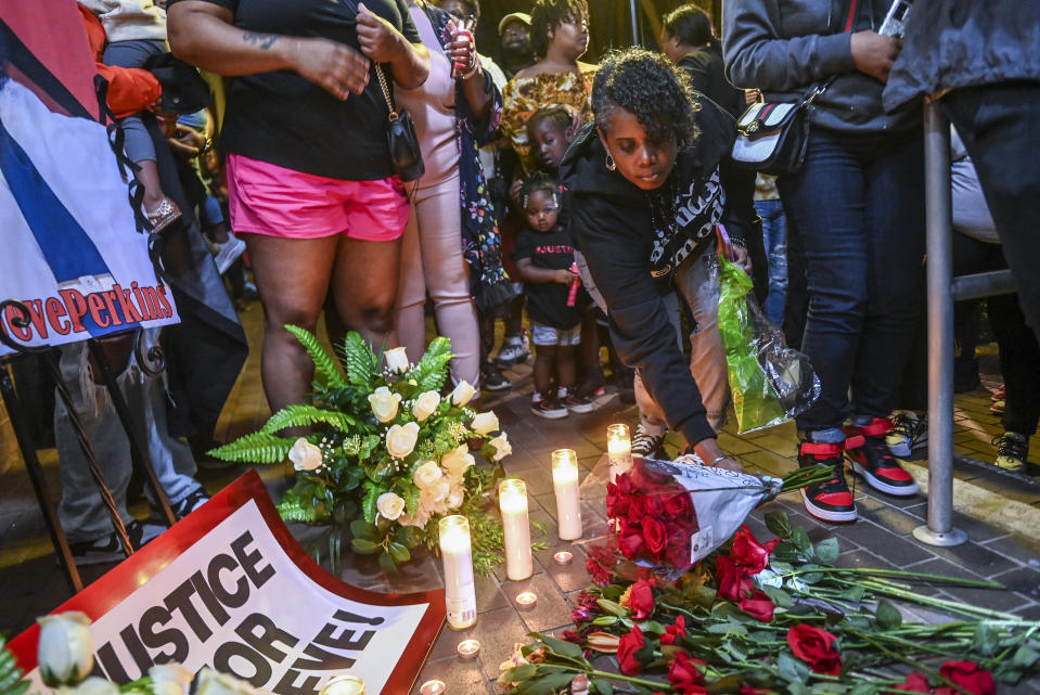 A woman leaves a bouquet of roses at a makeshift memorial during a vigil for Stephen Perkins outside Decatur, Ala. City Hall/Police Department, Thursday, Oct. 5, 2023. Police shot and killed Perkins, 39, the week before in what began in an early morning confrontation with a tow truck driver trying to repossess a vehicle, police said. Perkins' family said that he was not behind on payments and the vehicle should not have been repossessed. (Jeronimo Nisa/The Decatur Daily via AP)