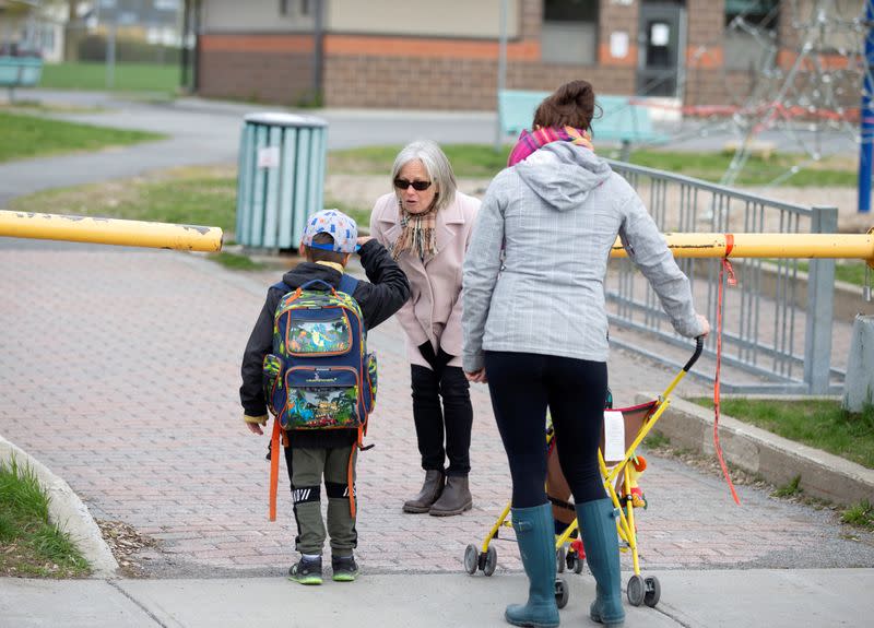 A student is greeted by a teacher as schools reopen outside the greater Montreal region in Saint-Jean-sur-Richelieu