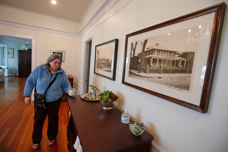 Anita Regan, owner, walks past a historic photo of the former Westview Mansion at the intersection of Main Street and Church Street in Fairhaven.