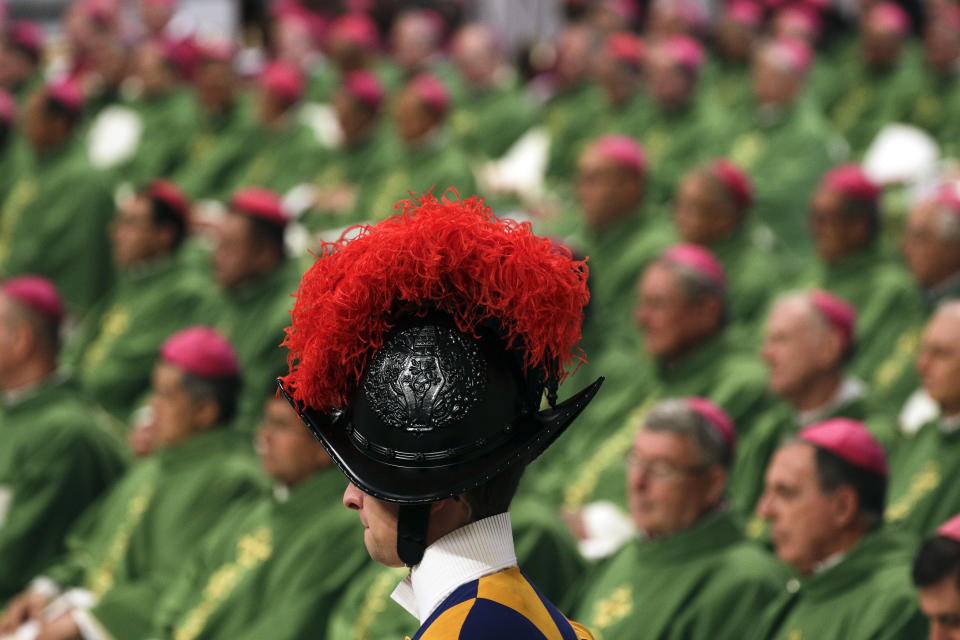 FILE - A Swiss guard is framed by prelates as Pope Francis celebrates an opening Mass for the Amazon synod, in St. Peter's Basilica, at the Vatican, Sunday, Oct. 6, 2019. Pope Francis is opening a divisive meeting on preserving the Amazon and ministering to its indigenous peoples, as he fends off attacks from conservatives who are opposed to his ecological agenda. Pope Francis is convening a global gathering of bishops and laypeople to discuss the future of the Catholic Church, including some hot-button issues that have previously been considered off the table for discussion. Key agenda items include women's role in the church, welcoming LGBTQ+ Catholics and how bishops exercise authority. For the first time, women and laypeople can vote on specific proposals alongside bishops. (AP Photo/Andrew Medichini, File)