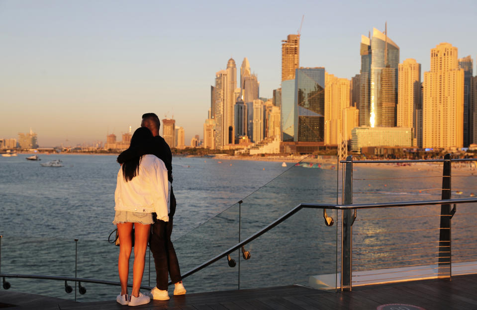 Tourists look at the skyline at sunset, in Dubai, United Arab Emirates, Tuesday, Jan. 12, 2021. Since becoming one of the world's first destinations to open up for tourism, Dubai has promoted itself as the ideal pandemic vacation spot. With peak tourism season in full swing, coronavirus infections are surging to unprecedented heights, with daily case counts nearly tripling in the past month, but in the face of a growing economic crisis, the city won't lock down and can't afford to stand still. (AP Photo/Kamran Jebreili)