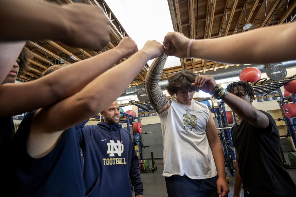 Football coach Evan Yabu, left, leads team members in a cheer at the end of a weight training session.