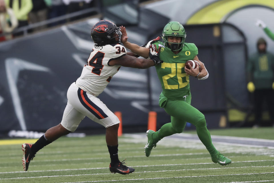 Oregon running back Travis Dye (26) tries to avoid Oregon State inside linebacker Avery Roberts (34) during the second half of an NCAA college football game in Eugene, Ore., Saturday, Nov. 30, 2019. (AP Photo/Amanda Loman)